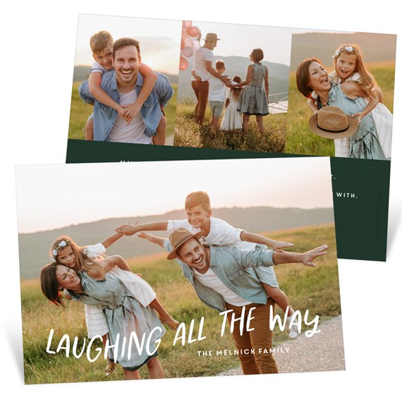 Holiday photo card with family of four in a sunset field, white handwritten headline and dark green back panel with extra photos
