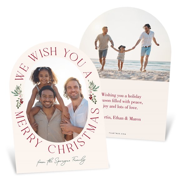 arched Christmas photo card with oval family photo, red greeting text, greenery sprigs and beige background