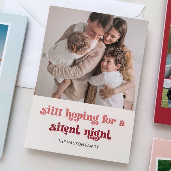 holiday photo card with family portrait and red script text on a cream panel