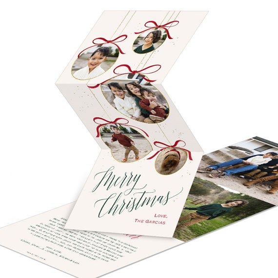 folded christmas photo card with oval ornament photo frames, red bows, gold accents and green 'merry christmas' script
