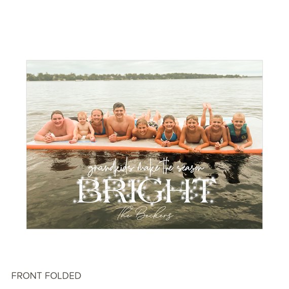 Folded holiday card featuring a family photo of children on a lake float with white script text 'BRIGHT' over the water.