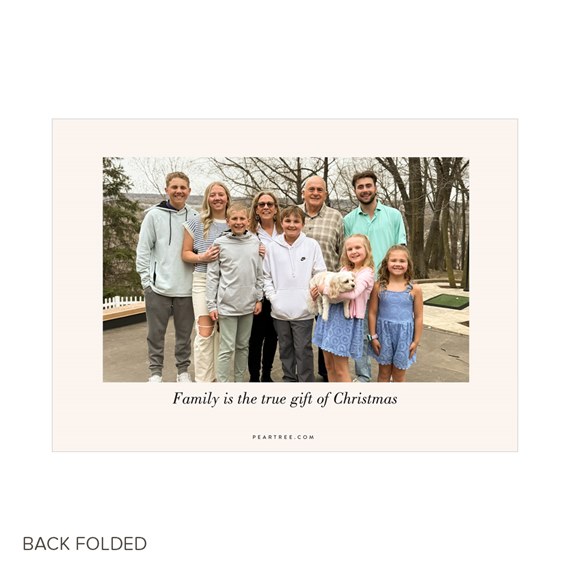 Folded Christmas photo card with centered family portrait and printed message 'Family is the true gift of Christmas' on a cream border.