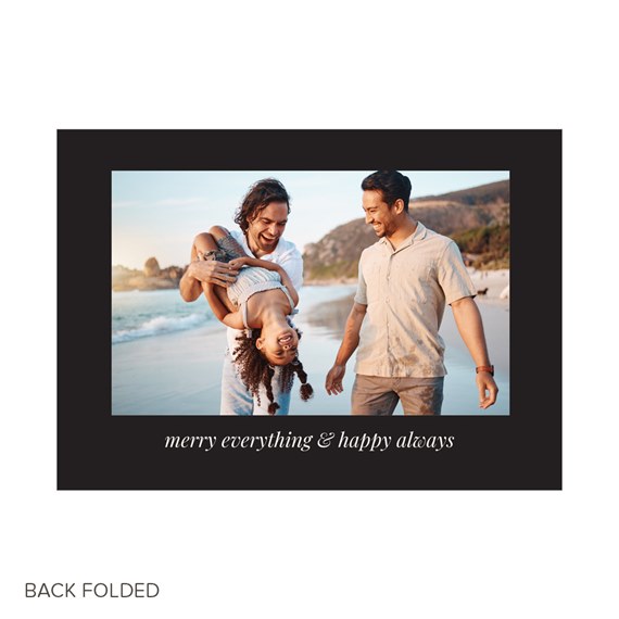 Folded holiday greeting card with family beach photo inside a black frame and scripted message at the bottom