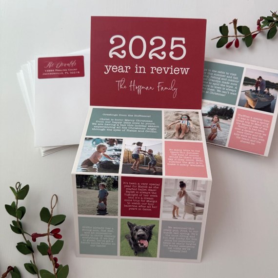 Folded A5 Christmas photo card with '2025 year in review' headline and multi-photo collage, shown with envelopes