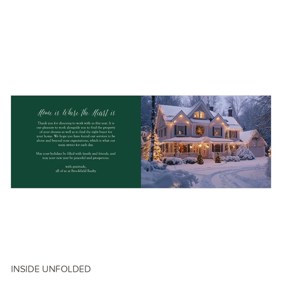 Inside spread of a business holiday card with a dark green panel containing a white holiday message and a photo of a snow-covered house decorated with warm string lights.