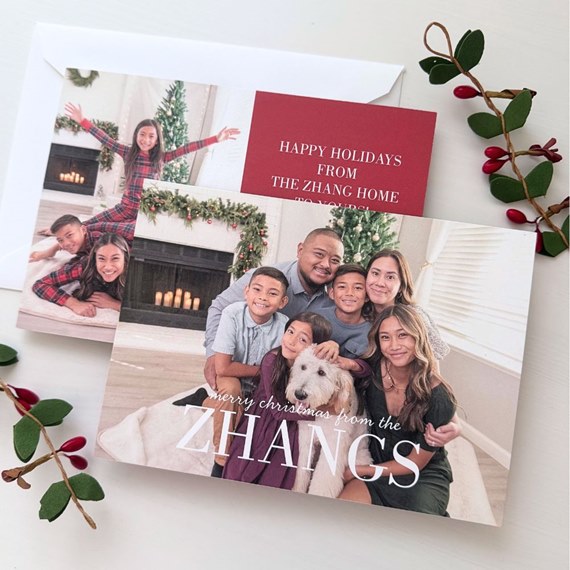 holiday photo card with family of six and dog in front of fireplace and Christmas tree with red greeting insert