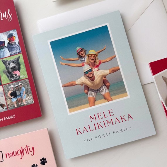 pale blue holiday card featuring a beach photo of three people on piggyback and red 