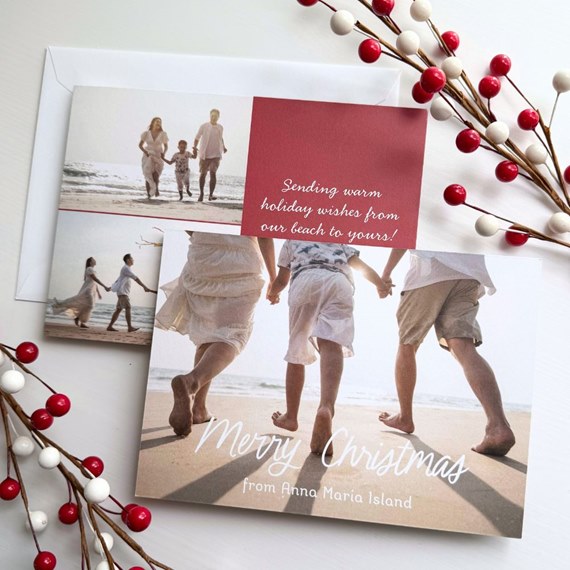 Christmas photo card showing family walking on a beach with a red message block and white scripted 'Merry Christmas' text
