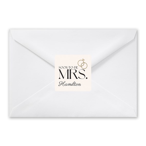 white envelope with a seal featuring text and wedding rings